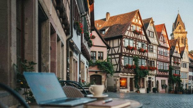 Cafe table with a laptop on a cobblestone street of half-timbered houses in a German town